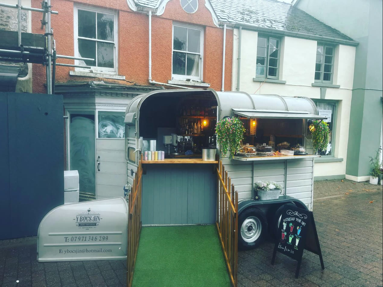The horsebox bar open on a street in Llandovery, fake-grass entrance and flower baskets